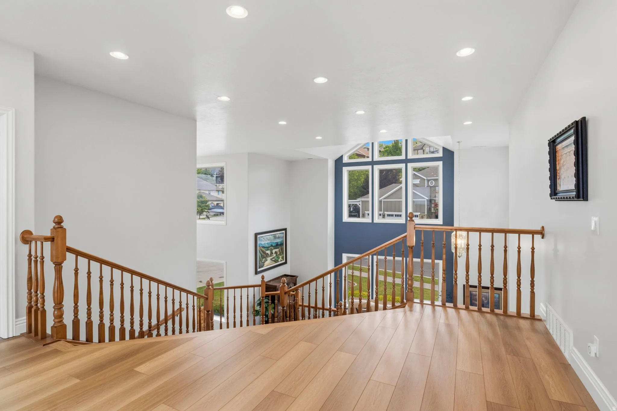 Hardwood-finish flooring extending throughout, featuring recessed lighting and a wood banister