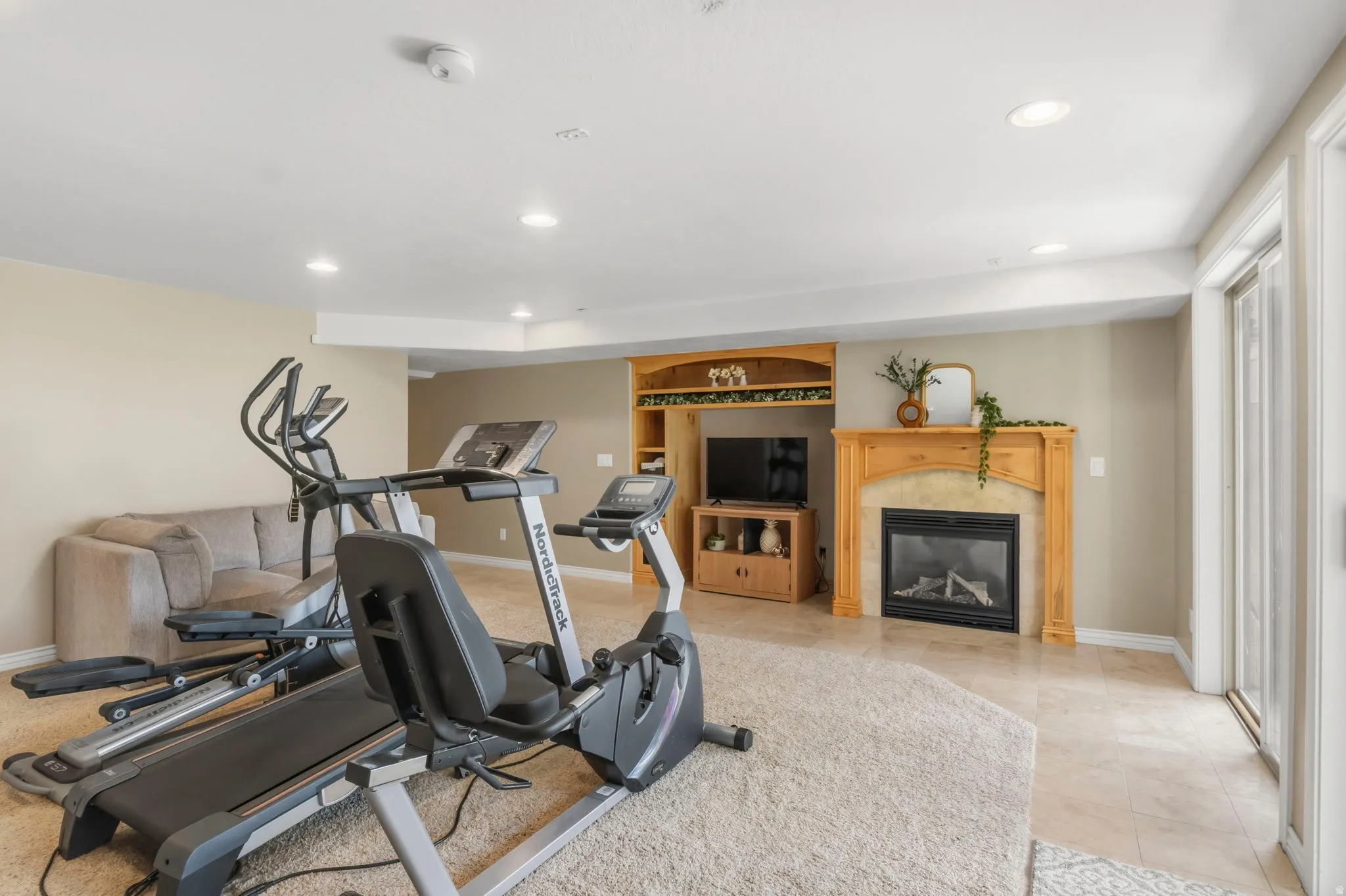 Spacious room featuring a fireplace with a wood mantel, built-in entertainment center, recessed lighting, and sliding glass door access
