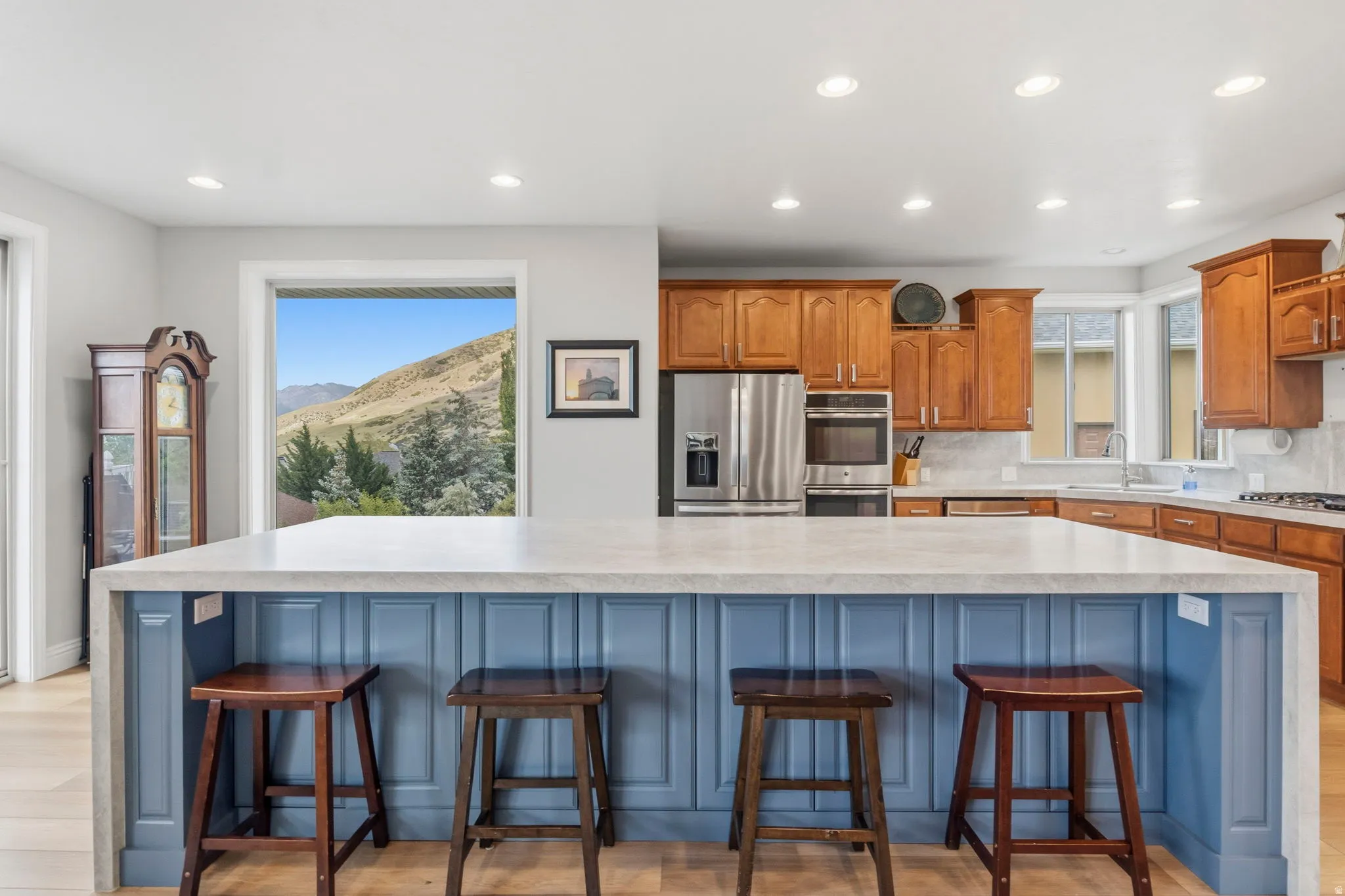 Kitchen featuring a large island with a light-colored countertop and blue paneled base