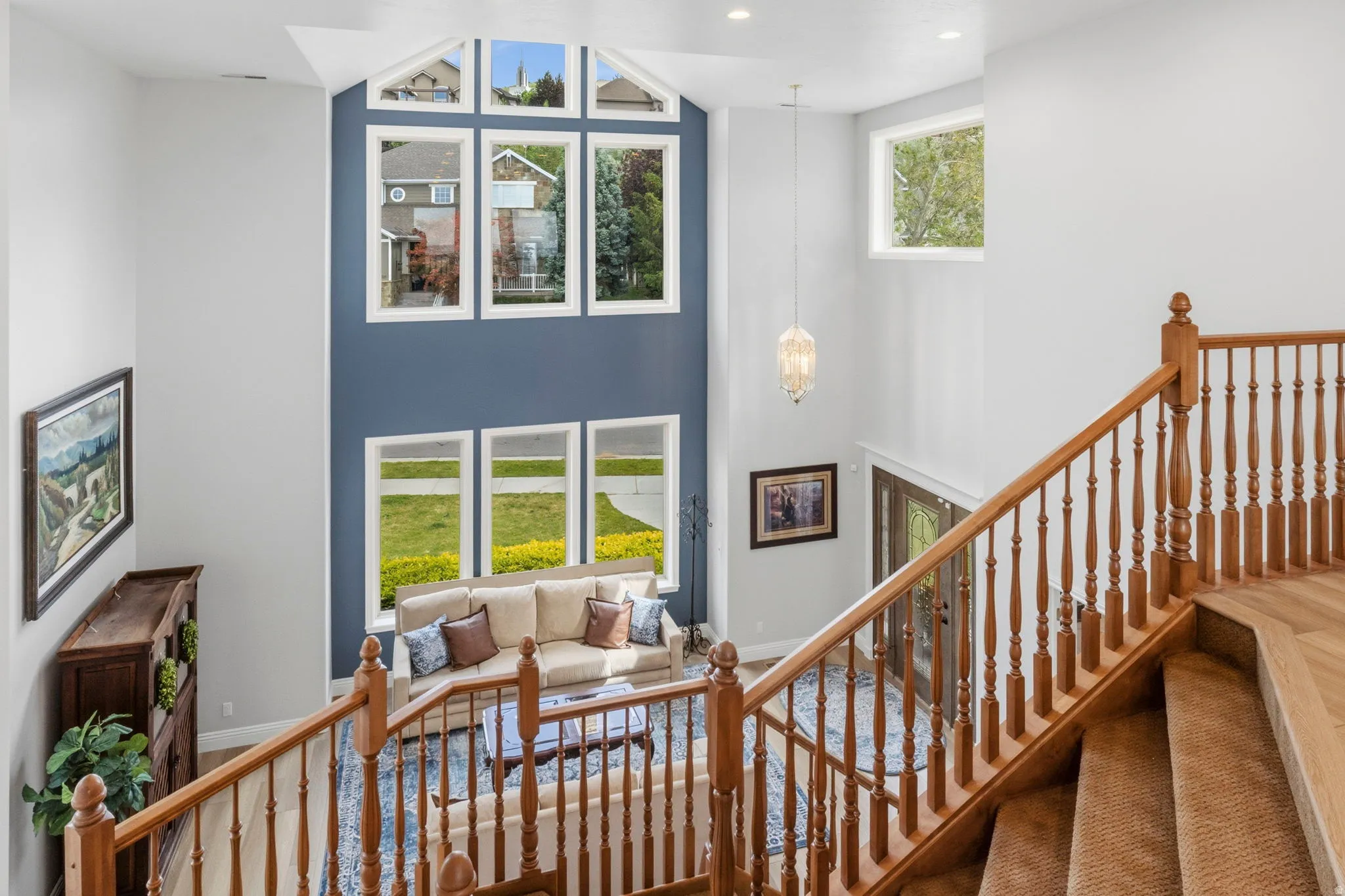 Two-story foyer featuring a tall wall of windows, hardwood flooring, and a grand staircase with wood balusters and handrail