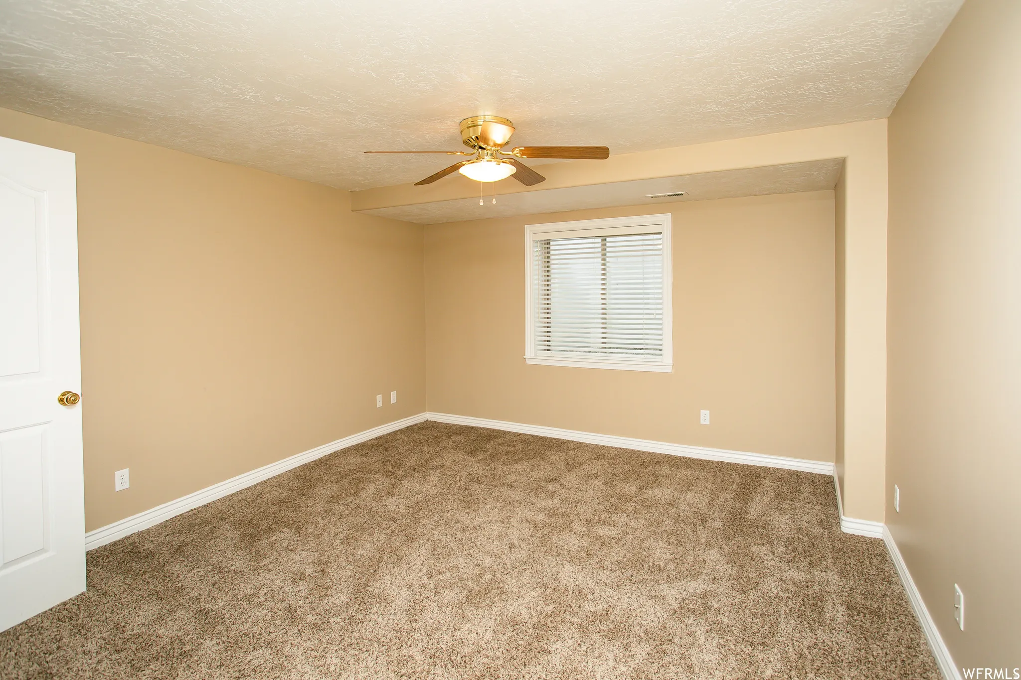 Carpeted room with neutral-toned walls, a white door, and white trim