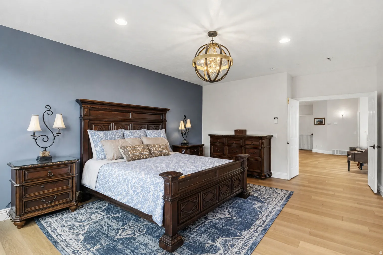 Spacious room featuring light wood-finish flooring, recessed lighting, and a prominent spherical chandelier