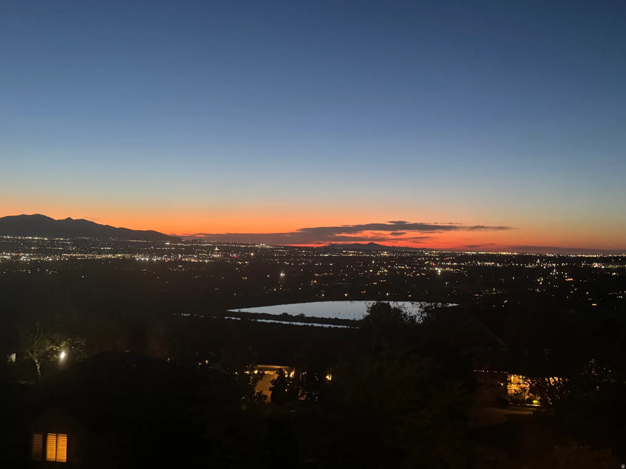 Expansive evening city lights and mountain backdrop, featuring a distant body of water