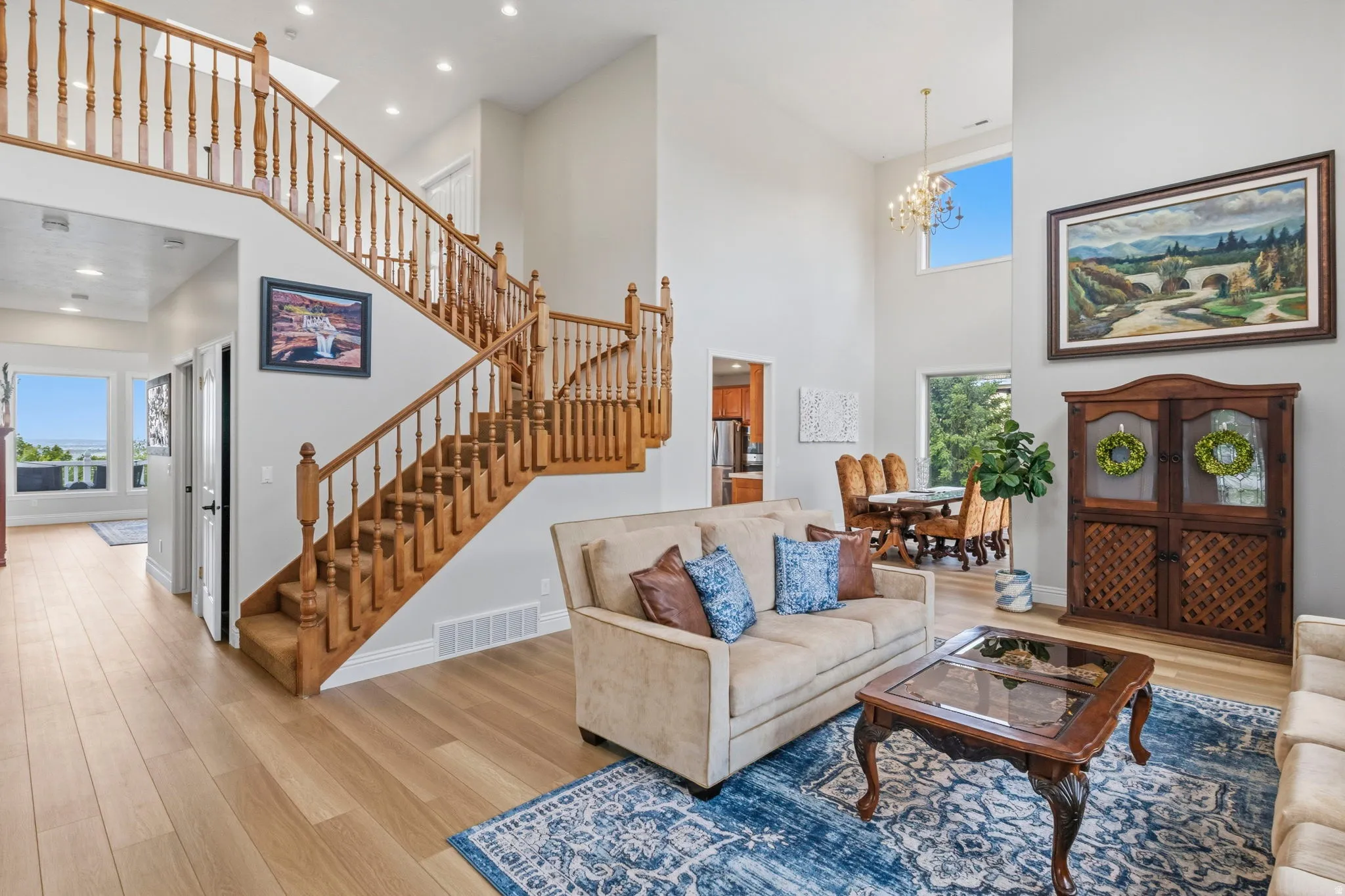 Grand entry featuring a light wood staircase with natural wood balusters, high ceilings, and light wood-finish flooring