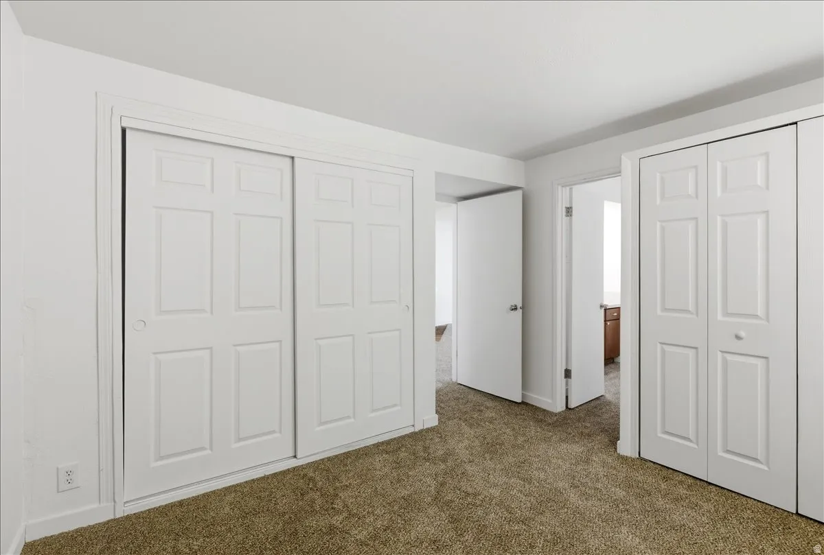 Spacious bedroom featuring neutral carpeting, white interior walls, and two white bi-fold closet doors