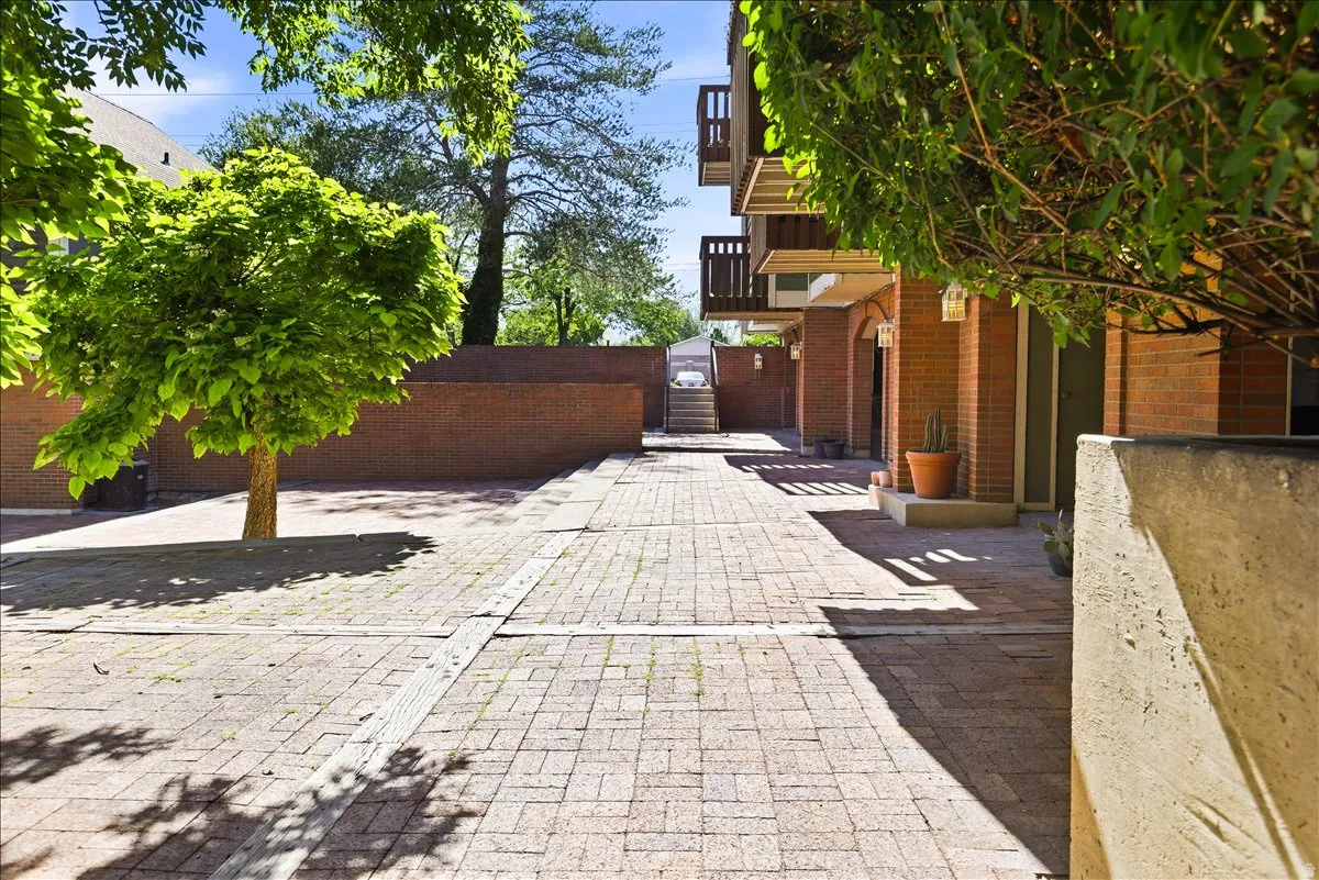 Brick paver walkway bordered by established trees and brick buildings