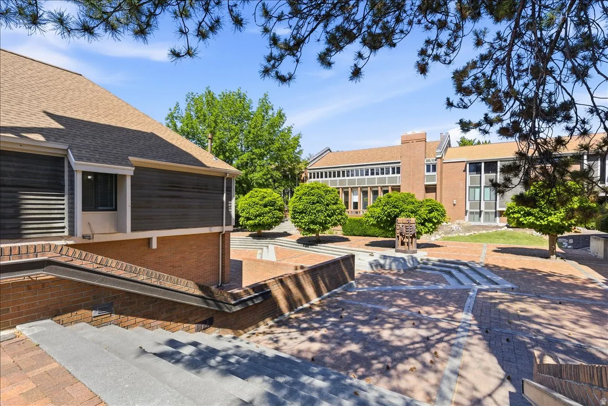 Spacious brick paved courtyard featuring tiered landscaping and mature plantings