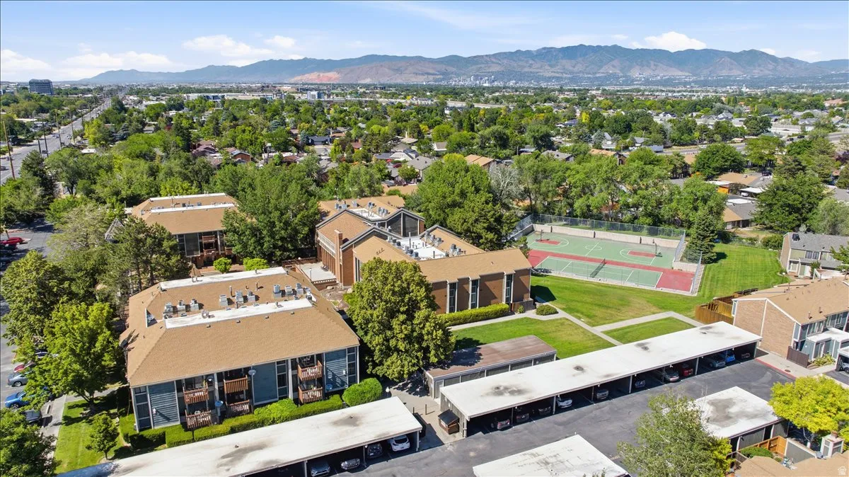 Multi-building complex featuring covered parking, mature landscaping, and an on-site sports court