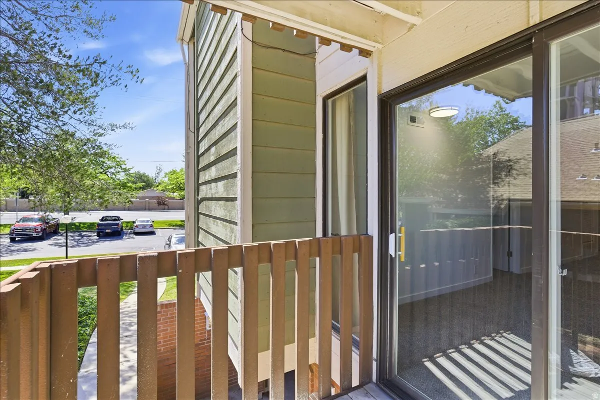 Balcony with wood railing, offering outdoor access through a glass sliding door