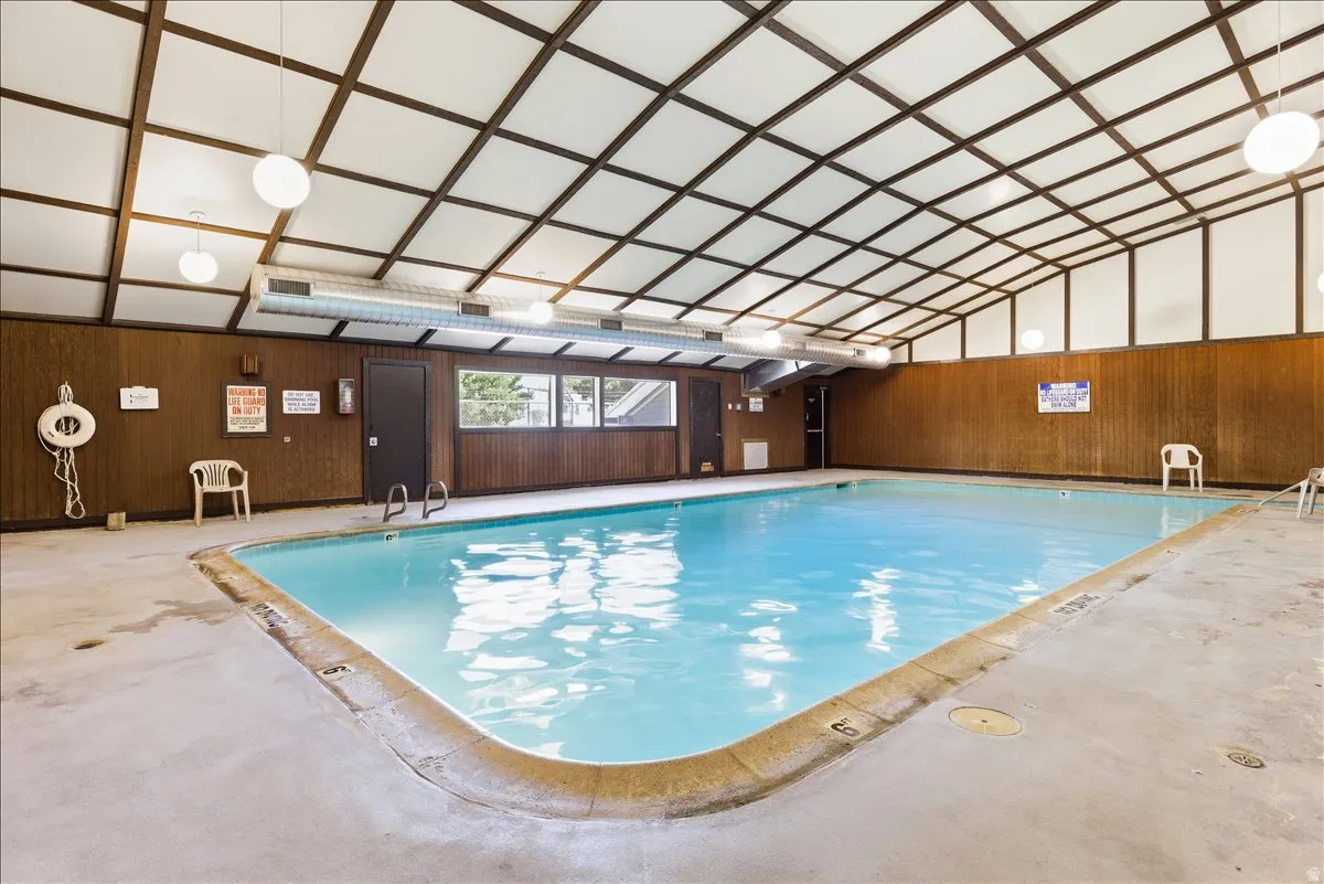 Indoor swimming pool featuring a trapezoidal shape, concrete decking, and wood-paneled walls