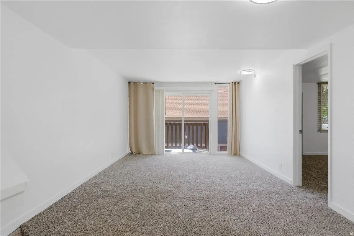 Carpeted room featuring a sliding glass door with balcony access