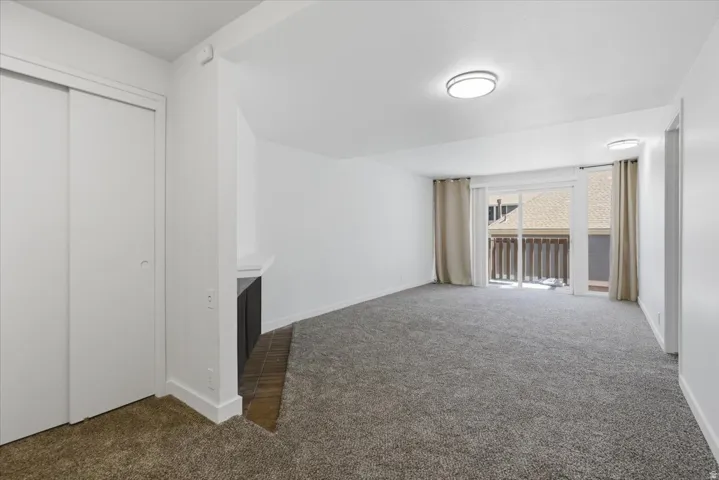 Carpeted living area featuring a built-in fireplace, sliding glass door to a balcony, and two recessed ceiling light fixtures