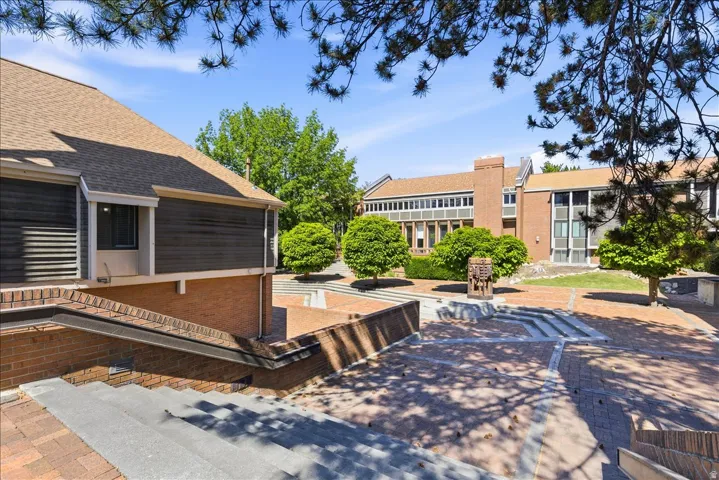 Spacious brick paved courtyard featuring tiered landscaping and mature plantings