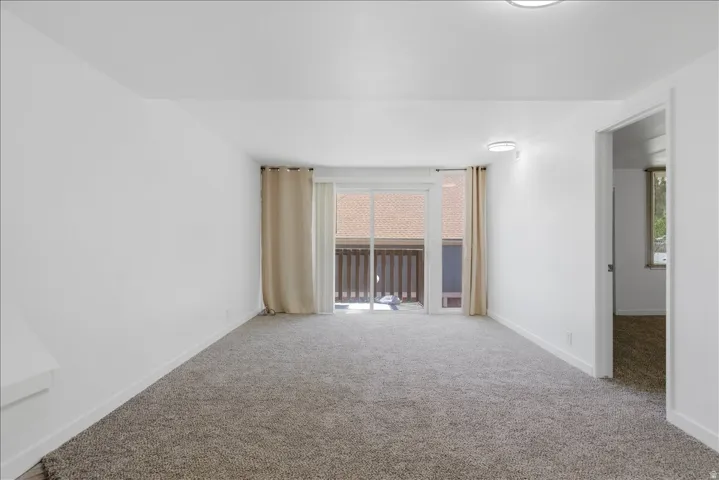 Carpeted room featuring a sliding glass door with balcony access