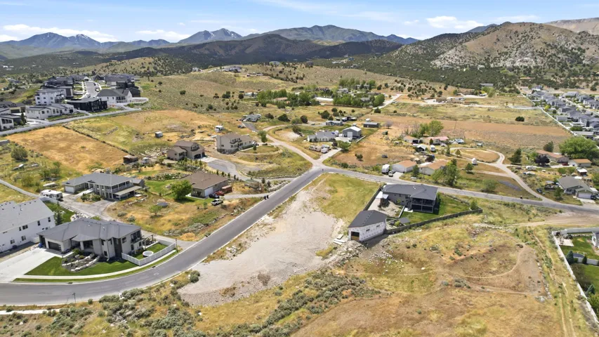 Expansive land parcel featuring existing infrastructure, paved road frontage, and mountain backdrops