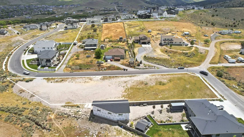 Cleared building lot positioned at a road intersection, featuring established roads and utility access