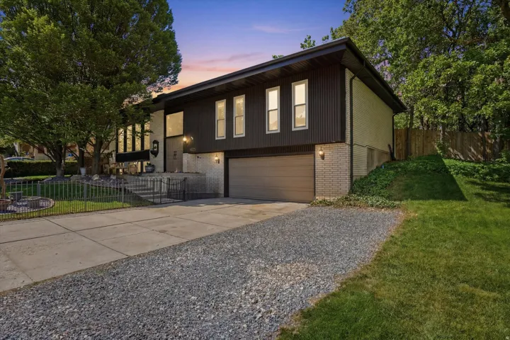 Split-level residence featuring a dark corrugated metal siding and light brick exterior