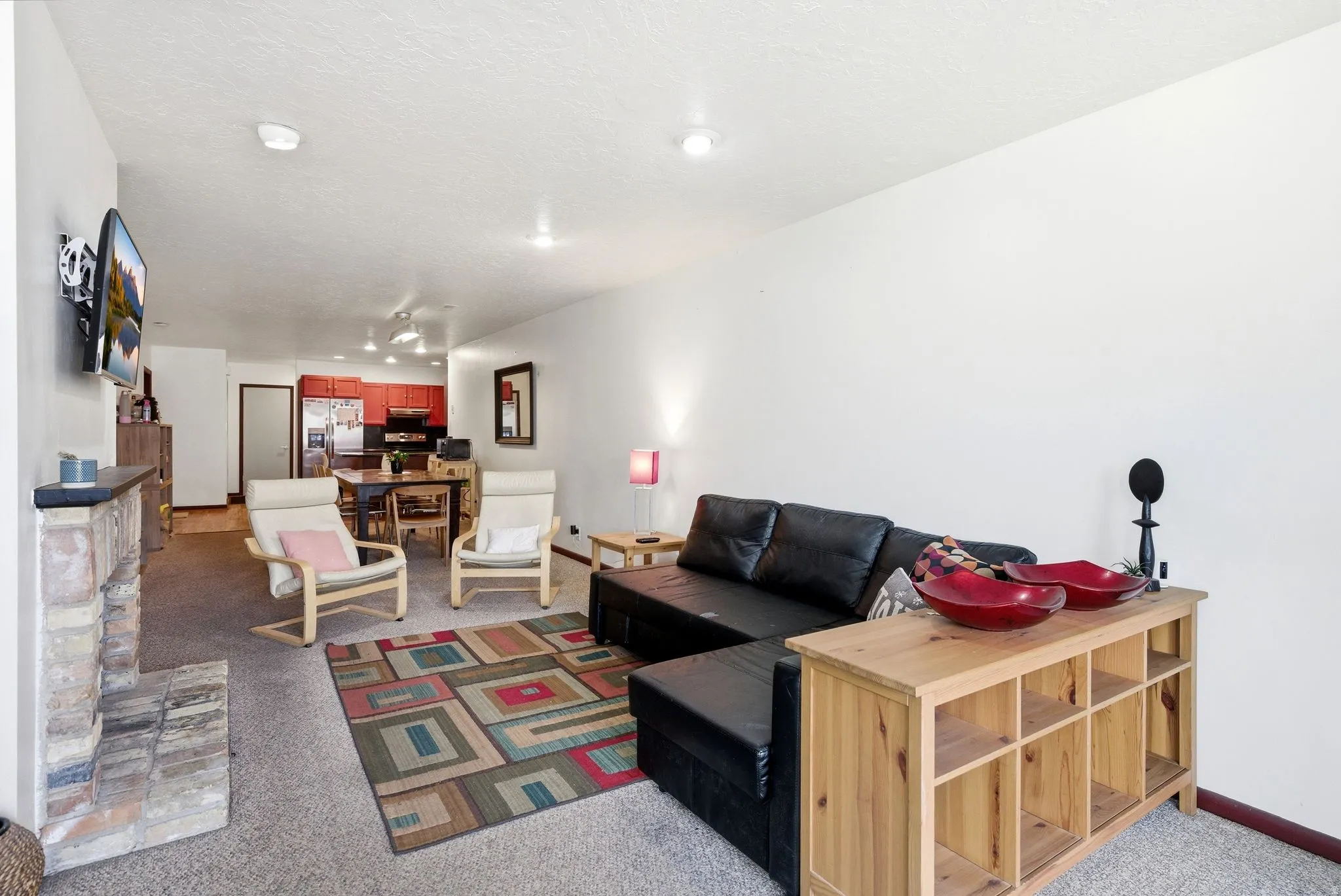 Open-concept living space featuring a stone fireplace, wall-mounted television, and recessed lighting