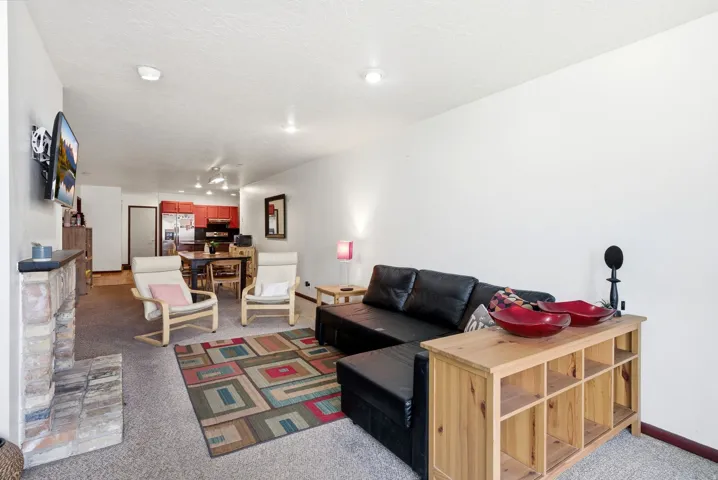 Open-concept living space featuring a stone fireplace, wall-mounted television, and recessed lighting