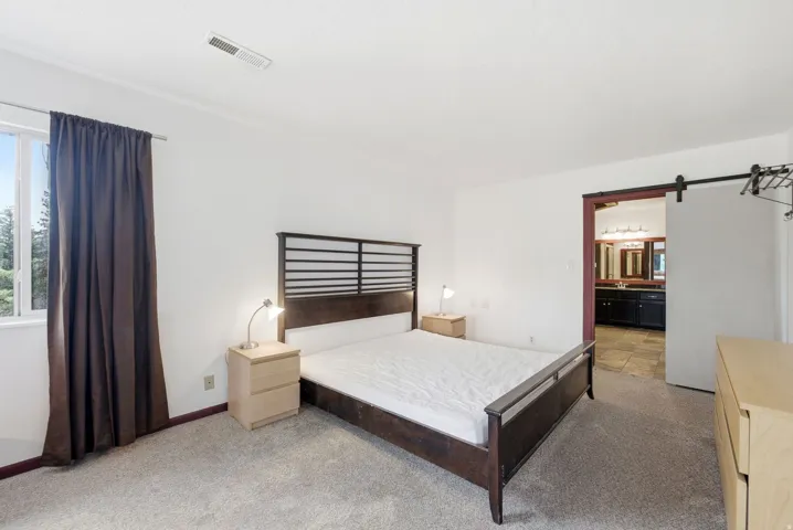Bedroom featuring light-colored carpeting and a window with dark curtains