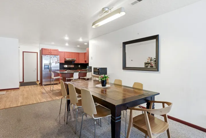 Open-concept dining area featuring a wood-finish table and carpet flooring