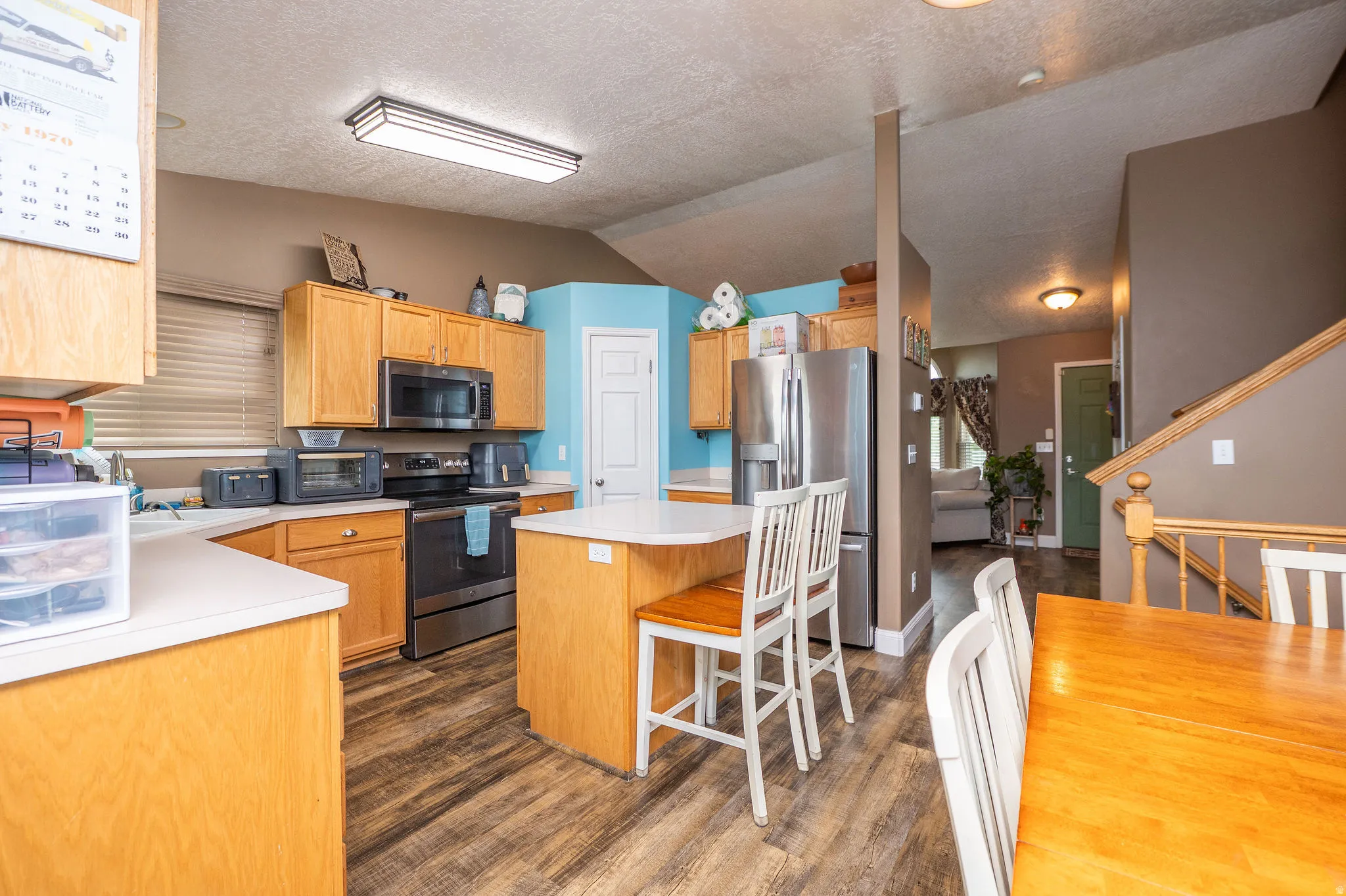 Kitchen featuring light wood cabinetry, white countertops, stainless steel appliances, and wood-finish flooring