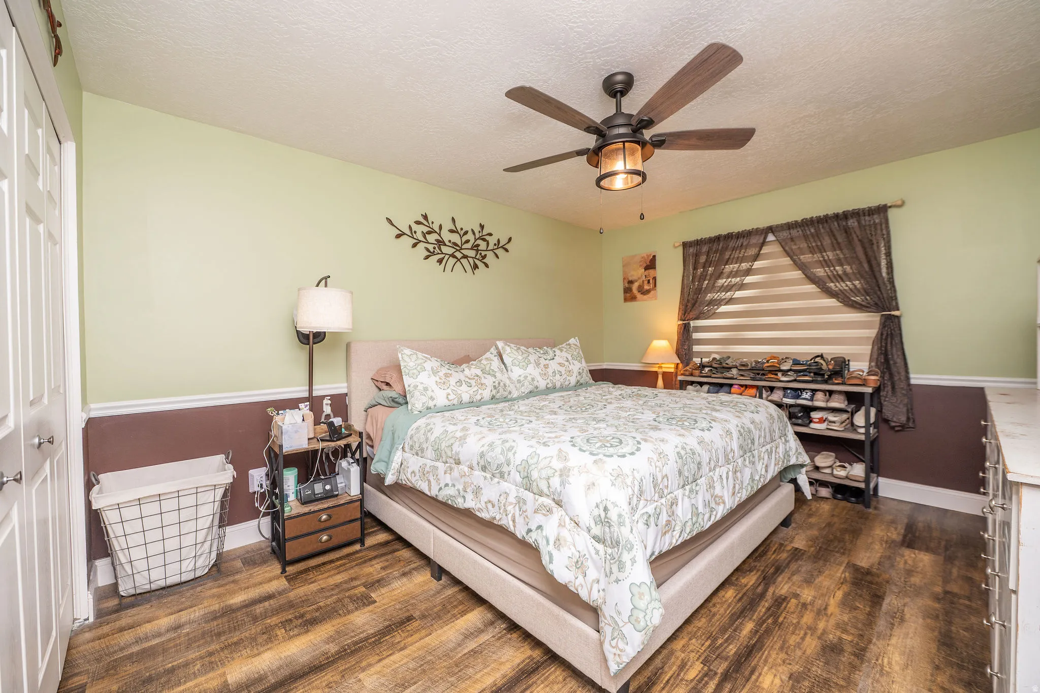 Spacious room featuring wood-finish flooring, a ceiling fan with integrated lighting, and a window with blinds