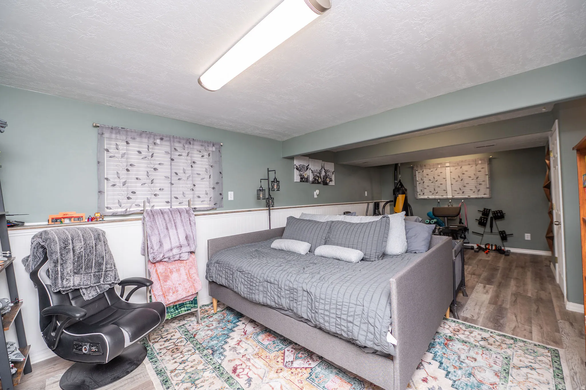 Finished room featuring wood-finish flooring, recessed lighting, and wainscoting details