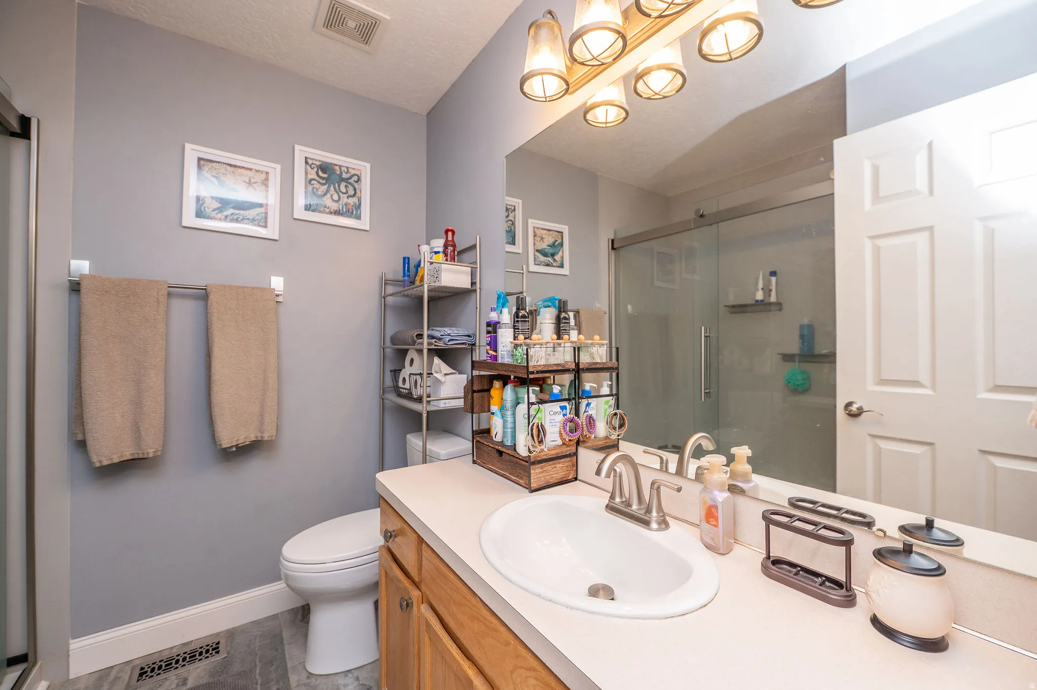 Bathroom featuring a single vanity with wood-finish cabinetry, a drop-in sink, and a brushed nickel faucet