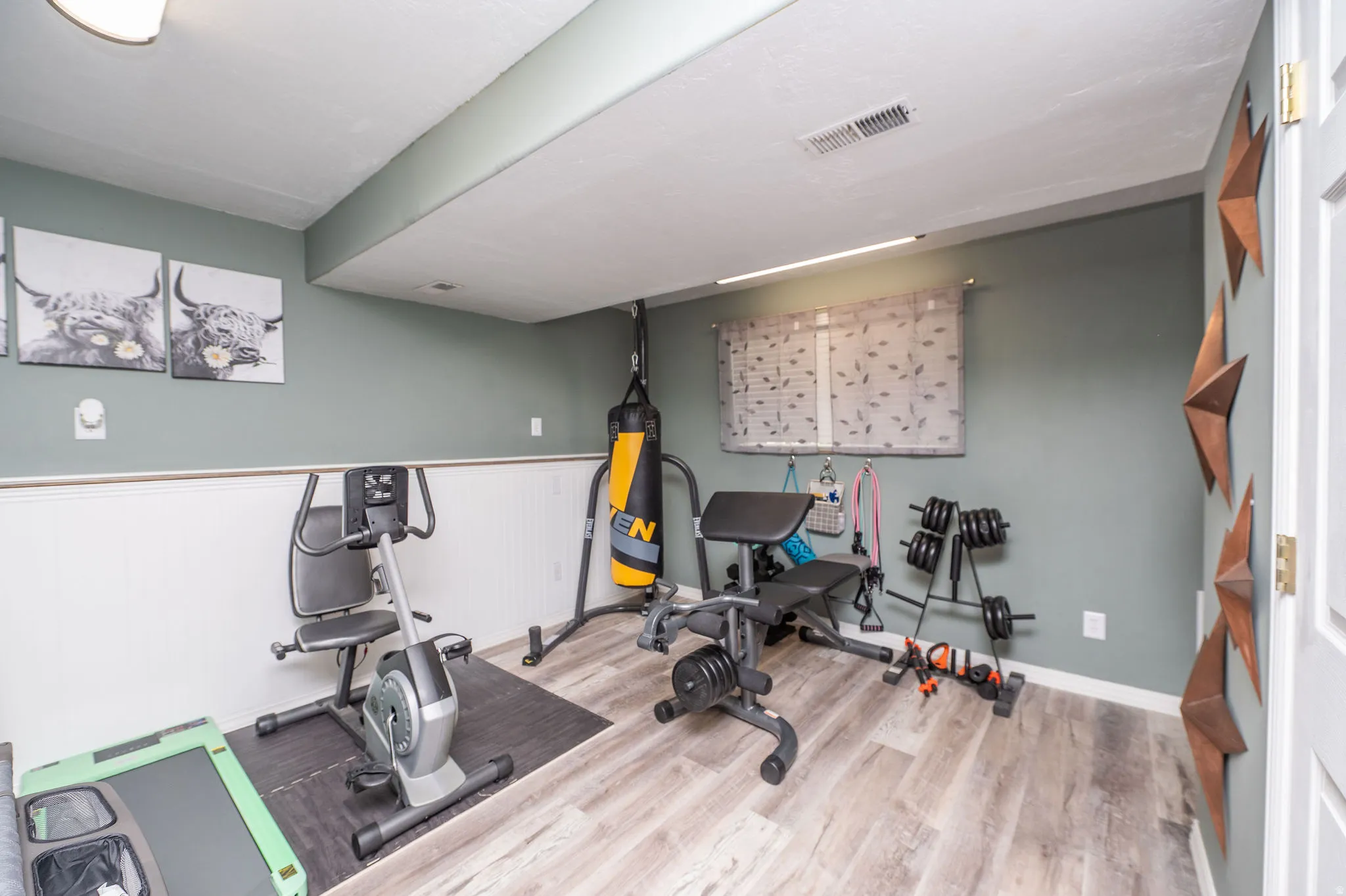 Versatile finished room featuring wood-finish flooring, a window with blinds, recessed lighting, and a two-tone wall treatment with wainscoting