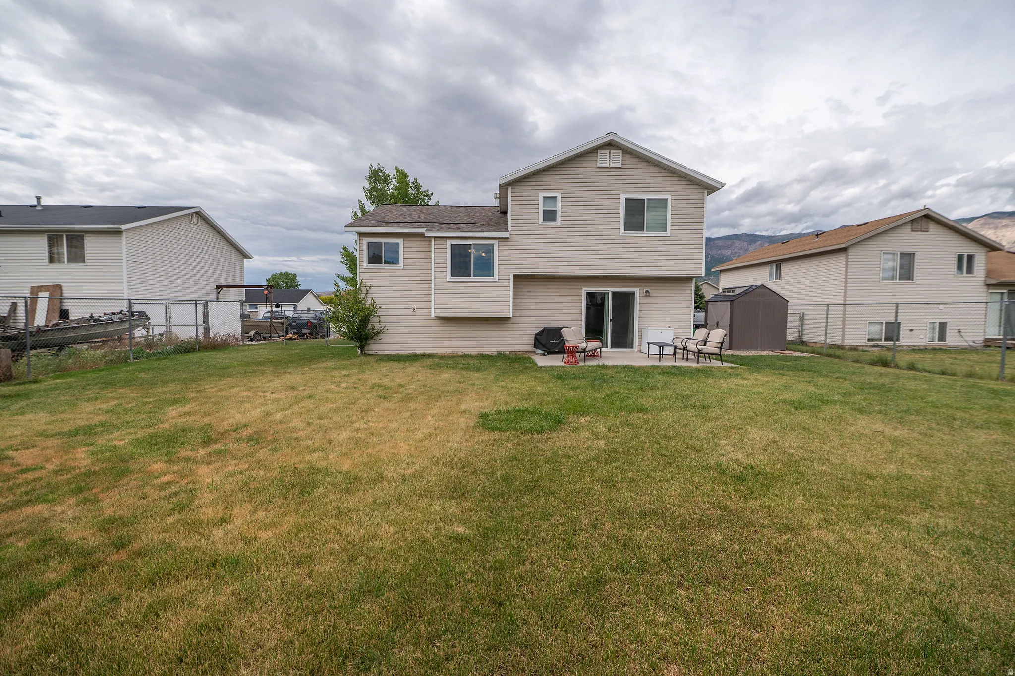 Expansive backyard featuring a patio with direct sliding door access, a storage shed, and a privacy fence