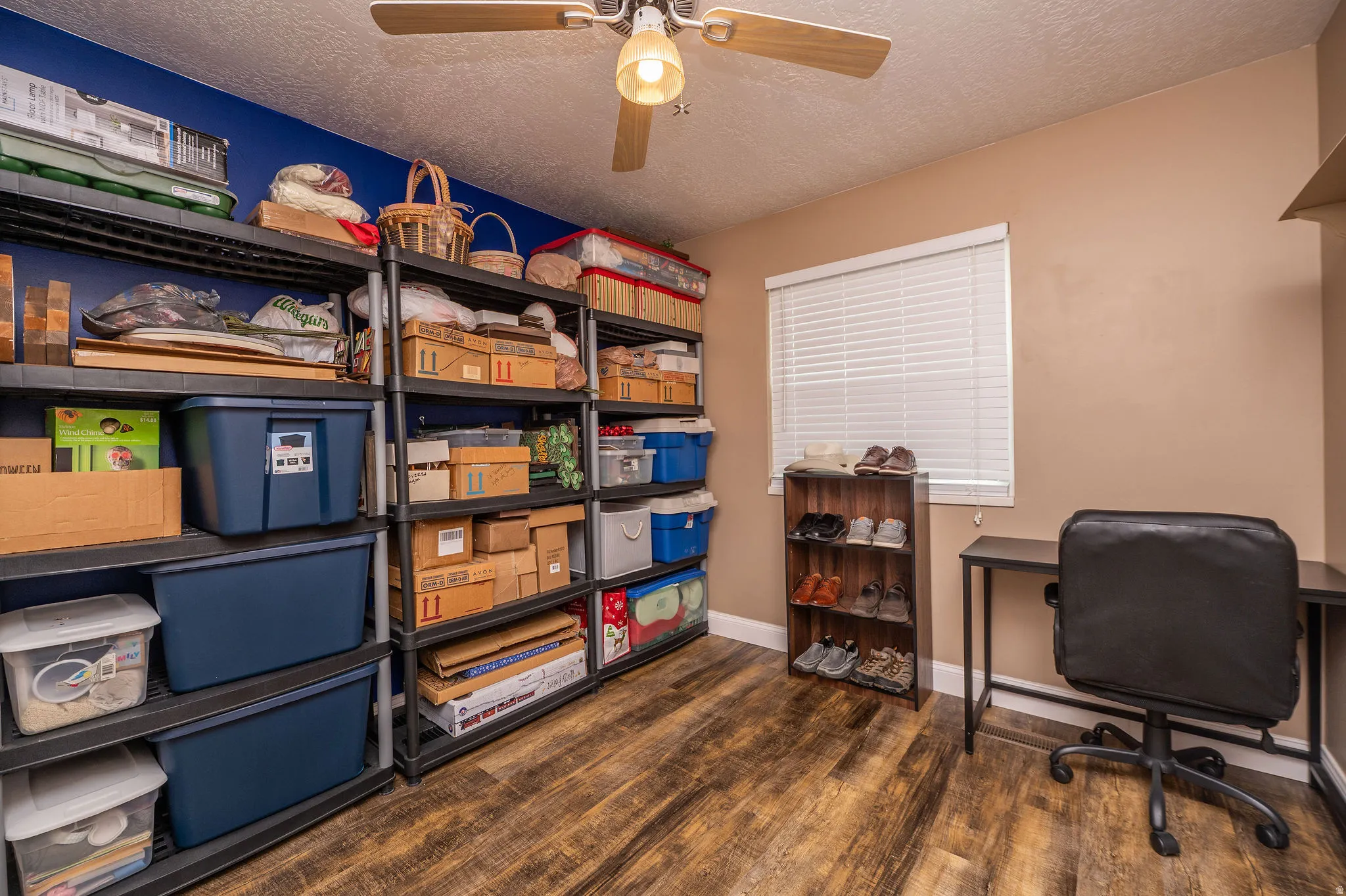 Room featuring wood-finish flooring, a ceiling fan with light fixture, and a window with blinds