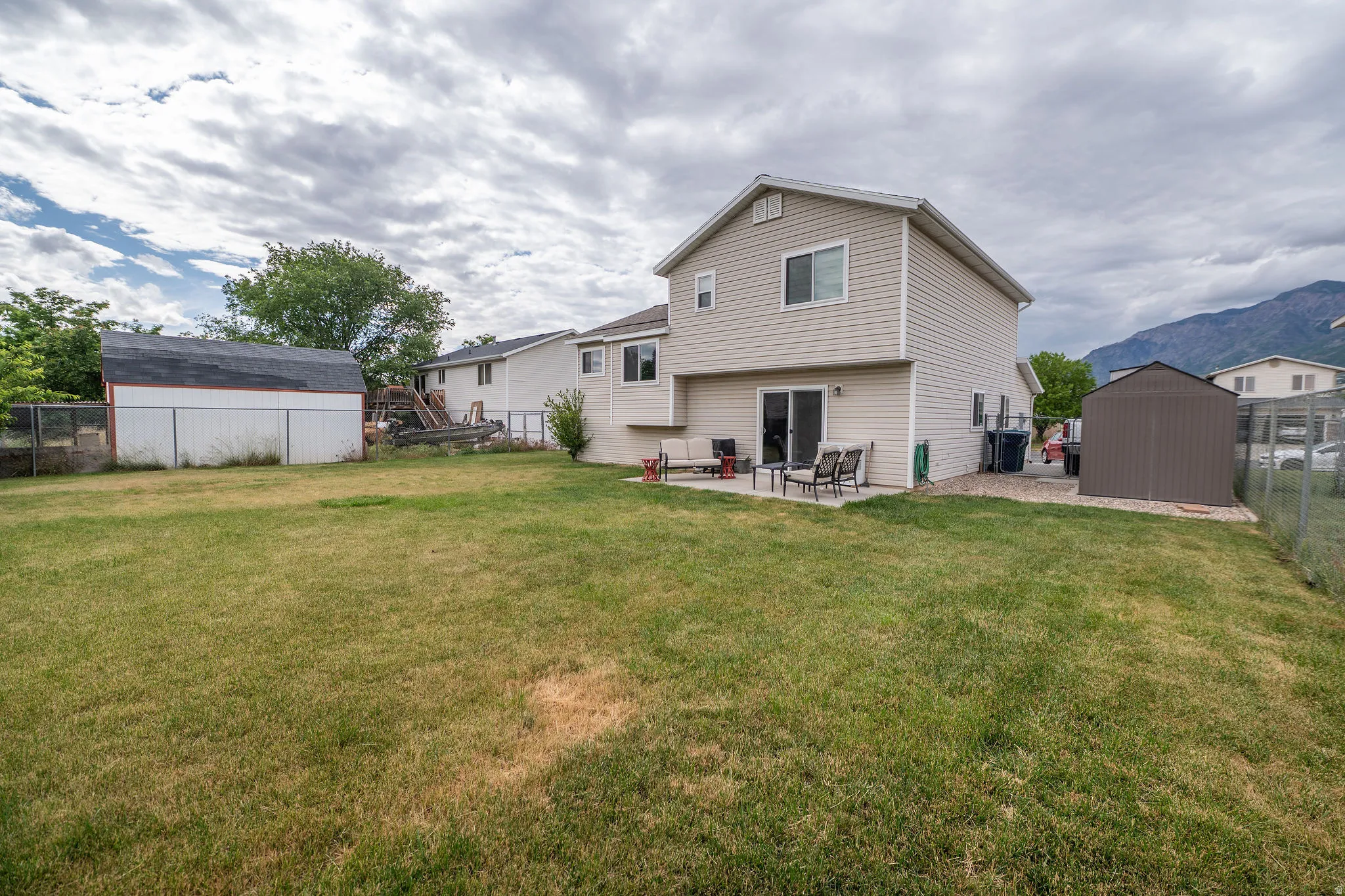 Expansive grass yard with a large patio and sliding glass door access to the residence