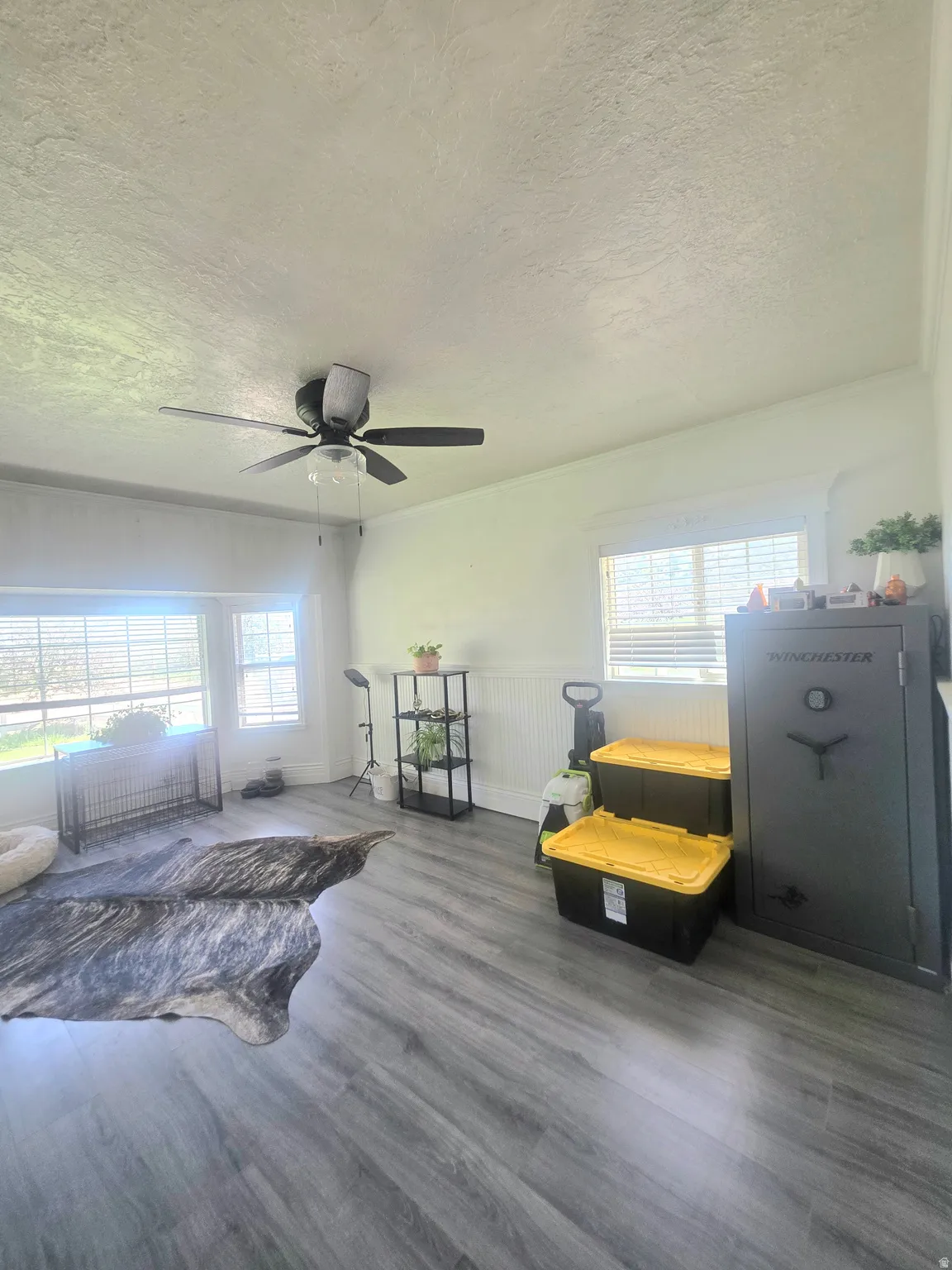 Spacious interior featuring wood-finish flooring, white walls, and a ceiling fan with integrated lighting
