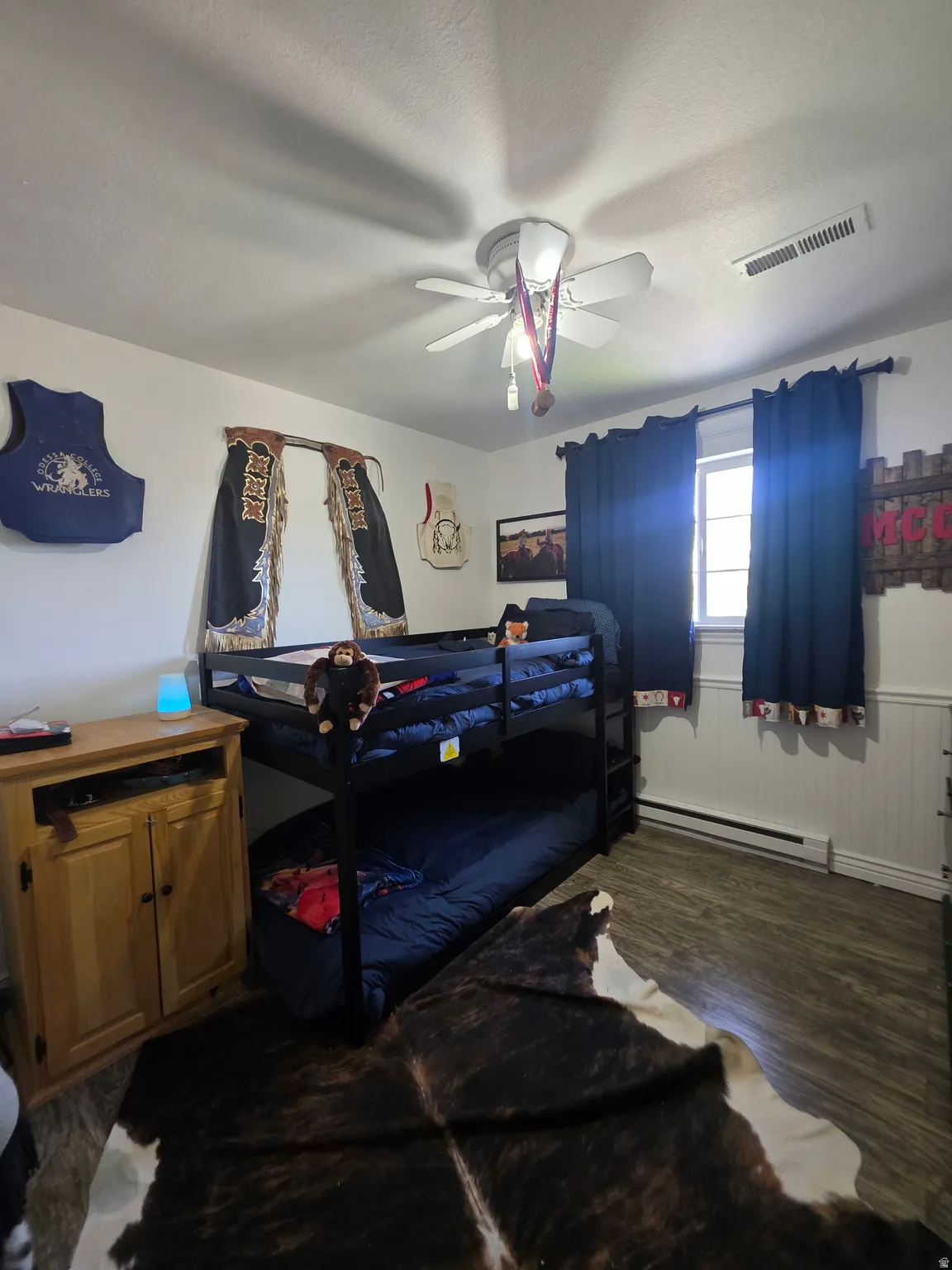 Room featuring wood-finish flooring, a window with dark drapes, and a white ceiling with a ceiling fan