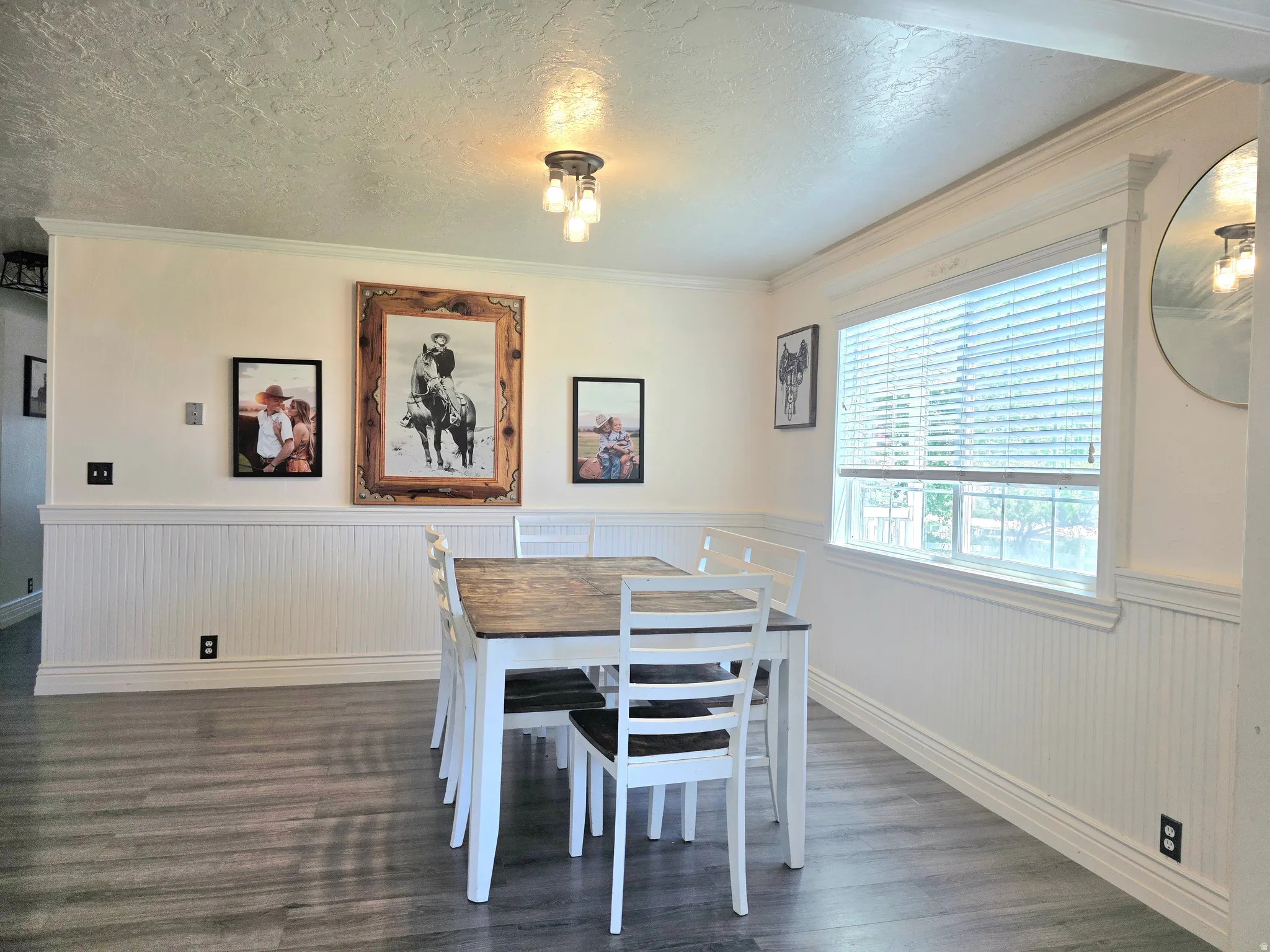 Dining area featuring wood-finish flooring, white wainscoting, and crown molding