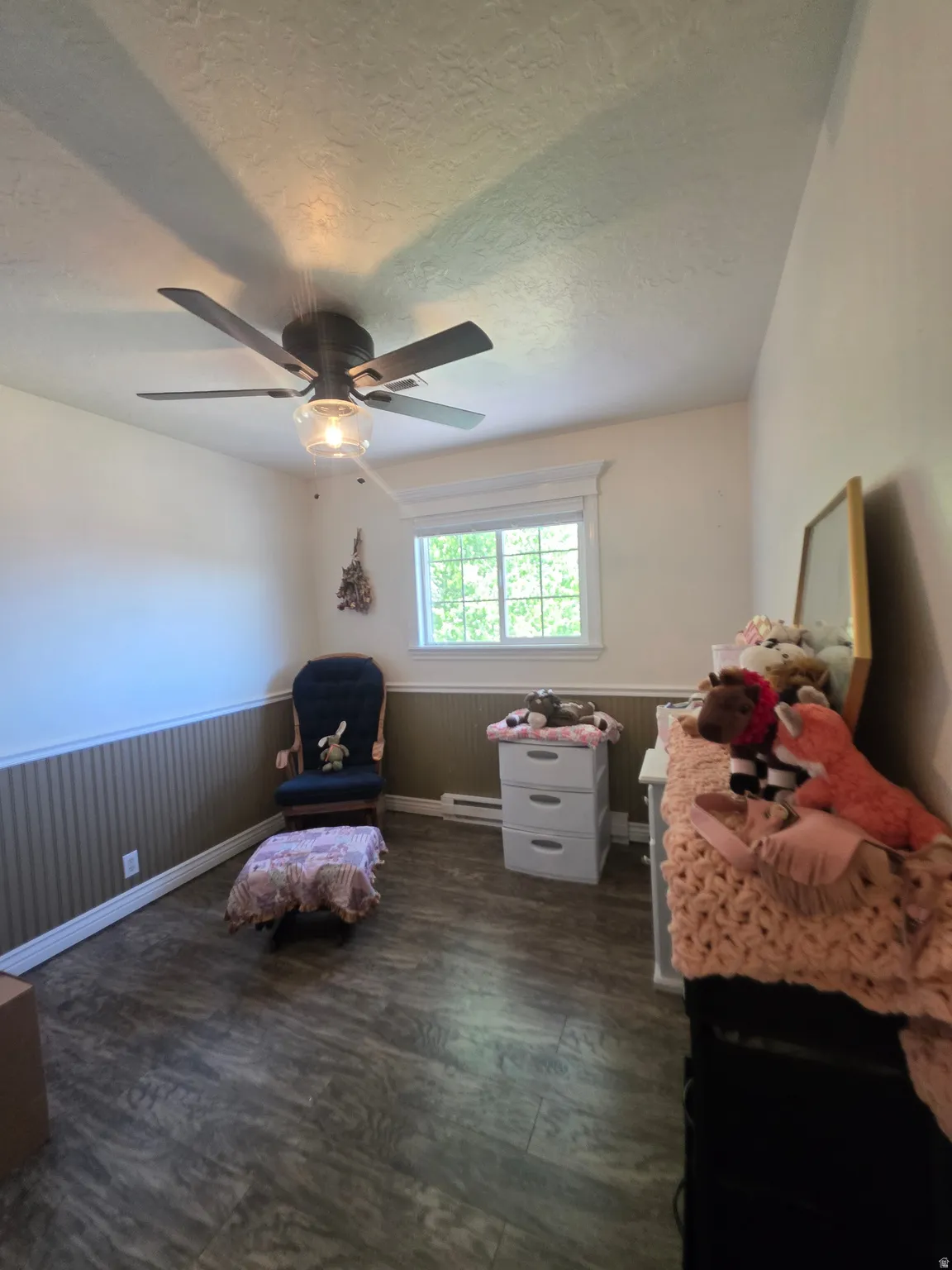 Room featuring wood-finish flooring, a ceiling fan with integrated lighting, and a white-trimmed window