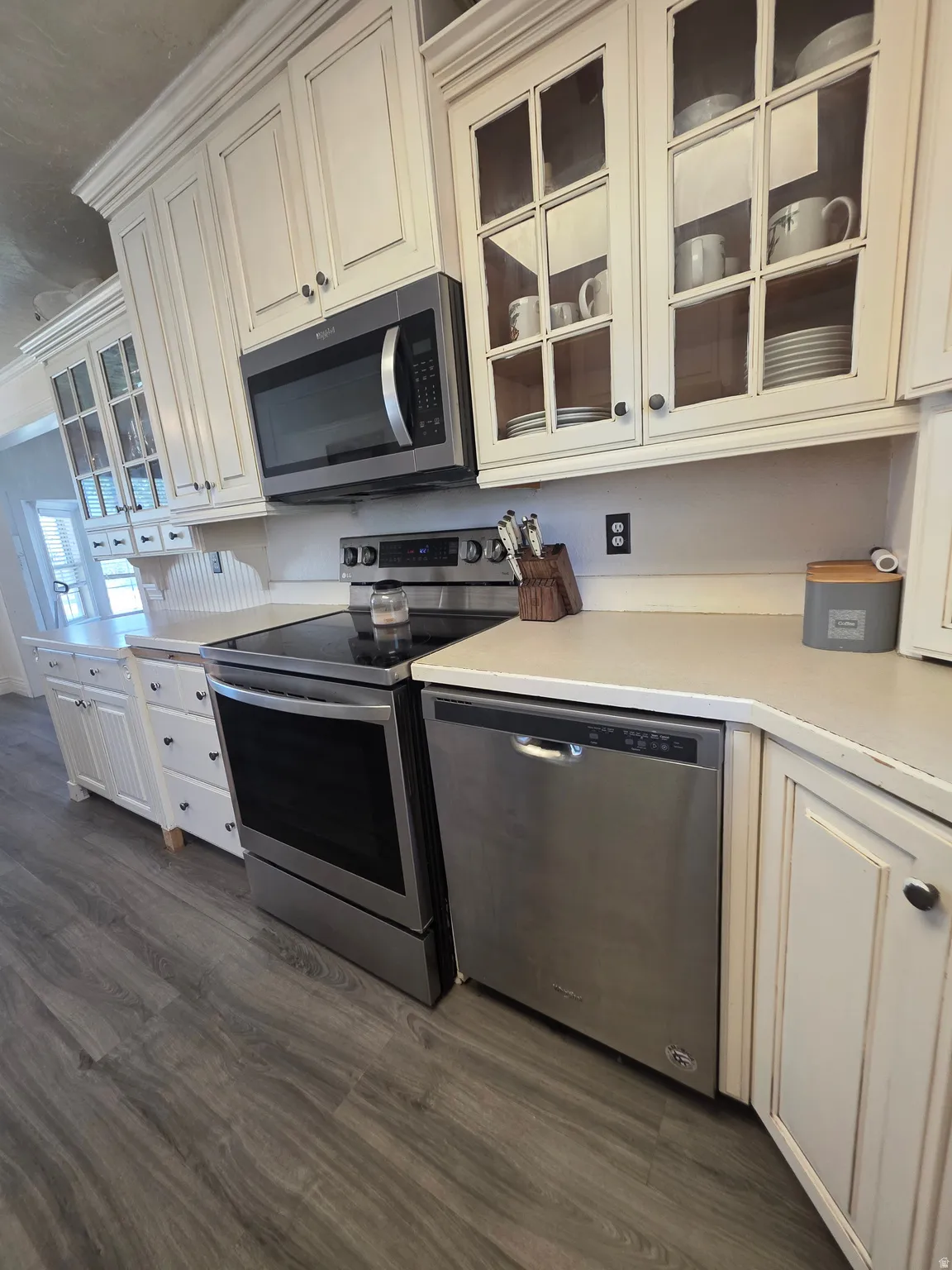 Kitchen featuring white cabinetry, stainless steel appliances, wood-finish flooring, and light-toned countertops