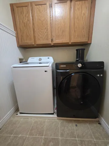 Dedicated laundry area featuring overhead wood cabinetry and wainscoting