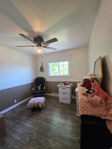 Room featuring wood-finish flooring, a ceiling fan with integrated lighting, and a white-trimmed window
