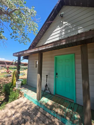Front entry with a vibrant turquoise door and a covered wood deck