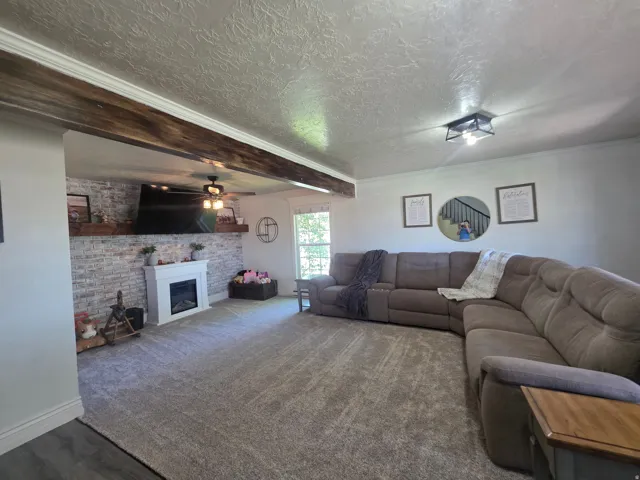 Spacious living area featuring a wood-finish ceiling beam, textured ceilings, and crown molding