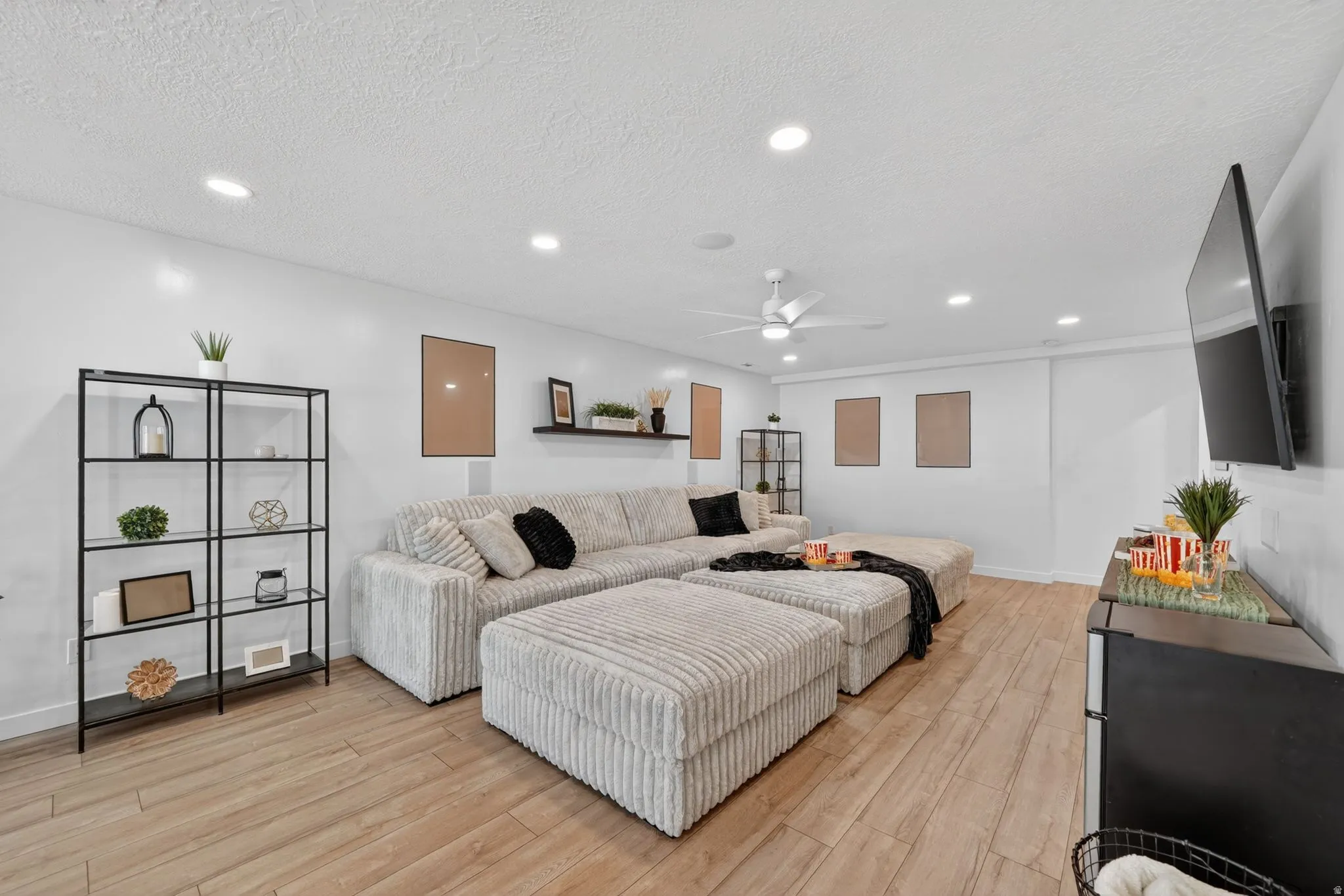 Spacious room featuring light wood-finish flooring, recessed lighting, and a ceiling fan