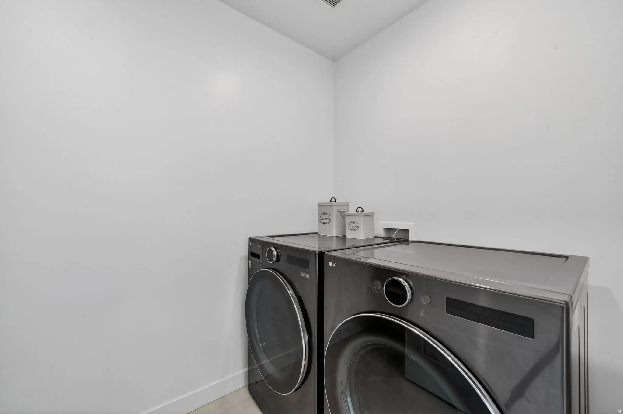 Dedicated laundry area with light wood-finish flooring and white painted walls