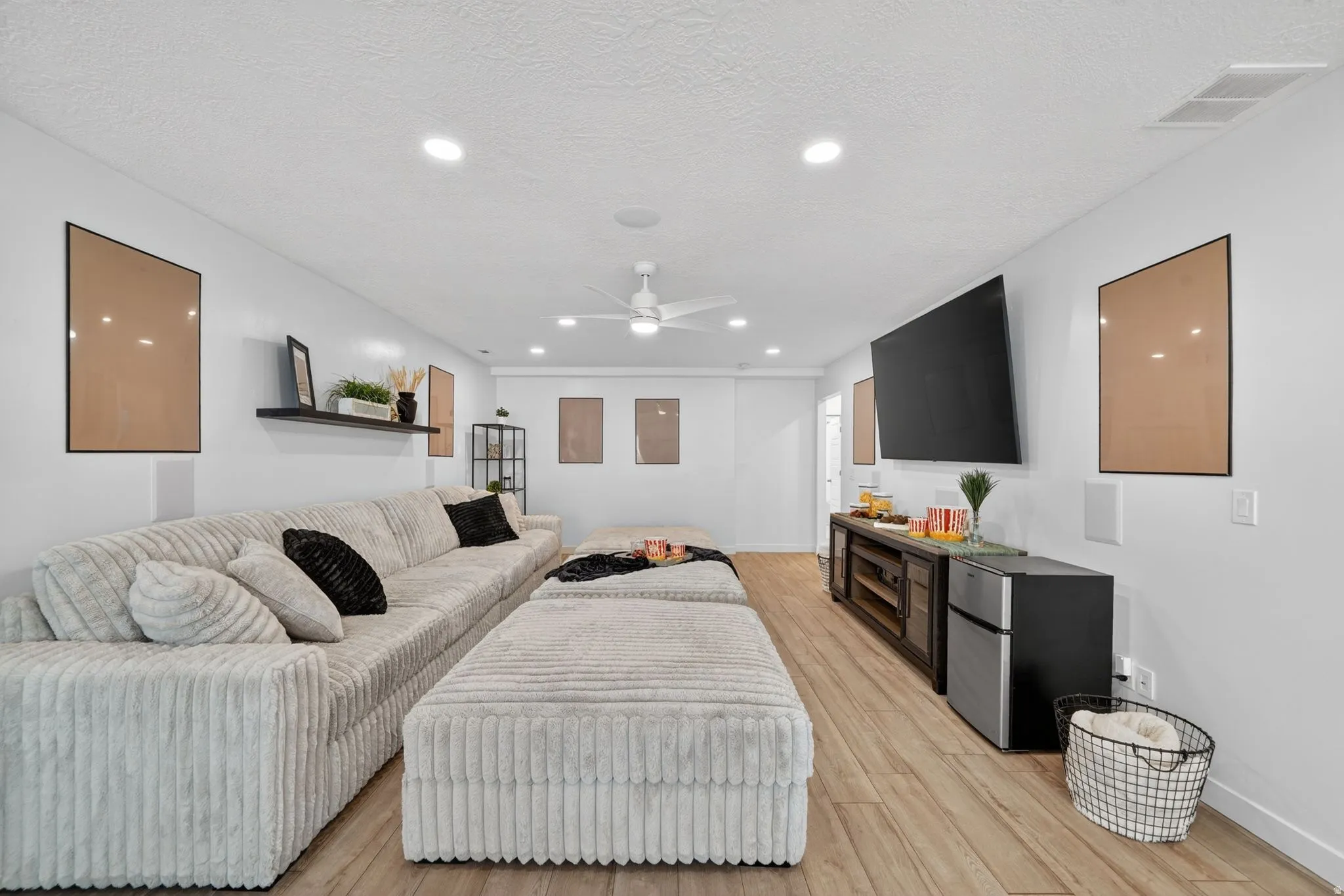 Spacious entertainment room featuring wood-finish flooring, recessed lighting, and a ceiling fan