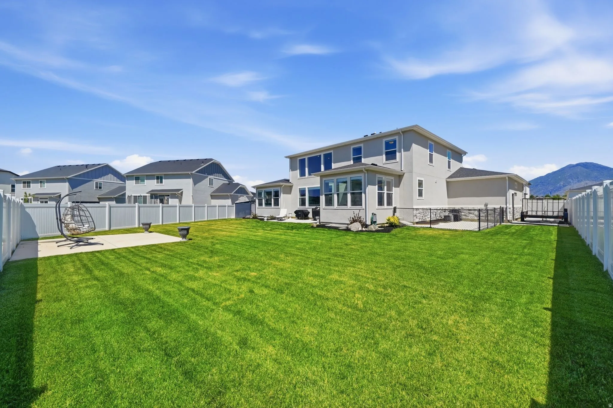 Expansive green lawn with a white vinyl privacy fence bordering the property