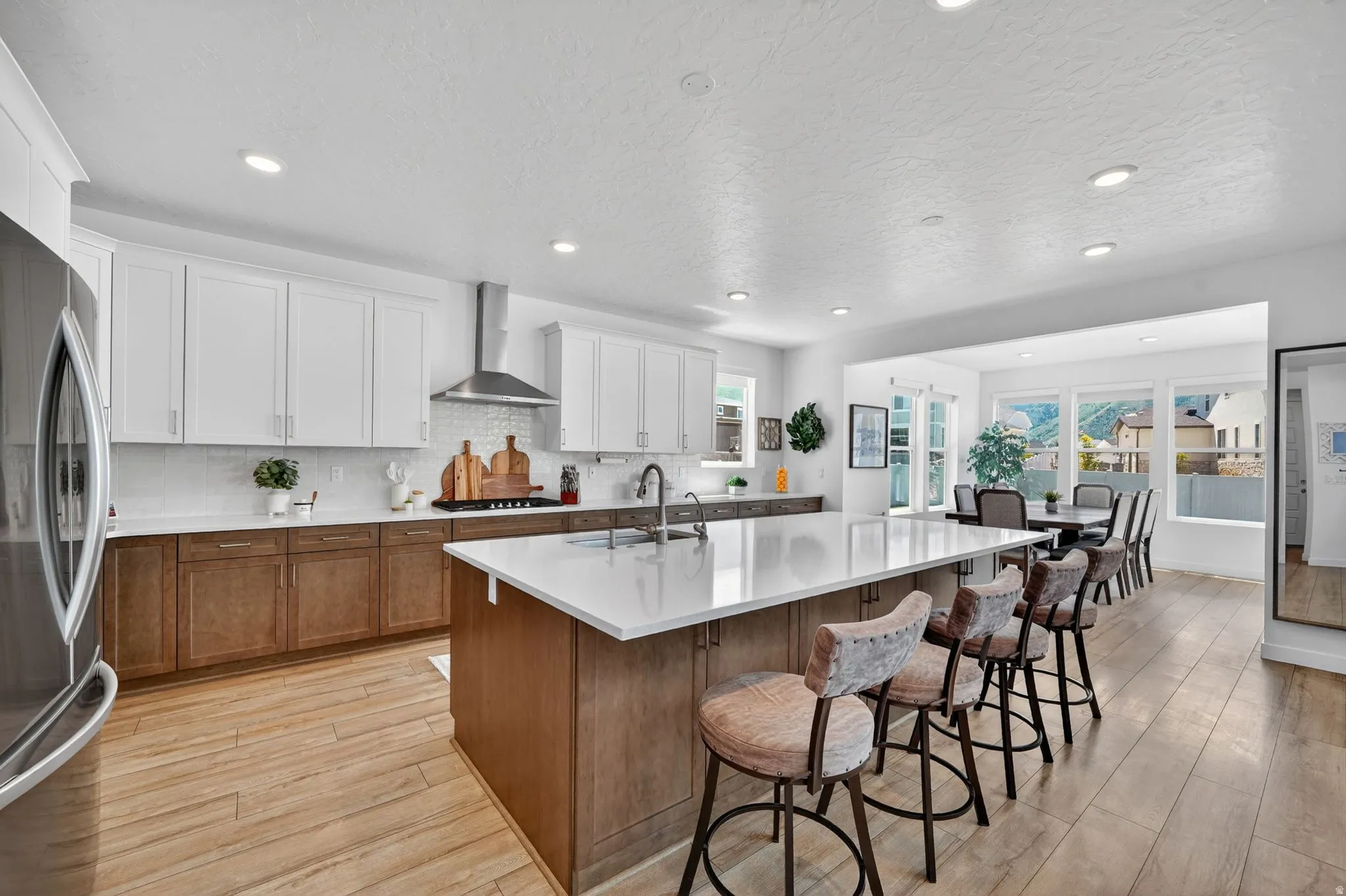 Spacious kitchen featuring an expansive central island with a light-toned countertop, two-tone cabinetry, stainless steel appliances, wood-finish flooring, and recessed lighting