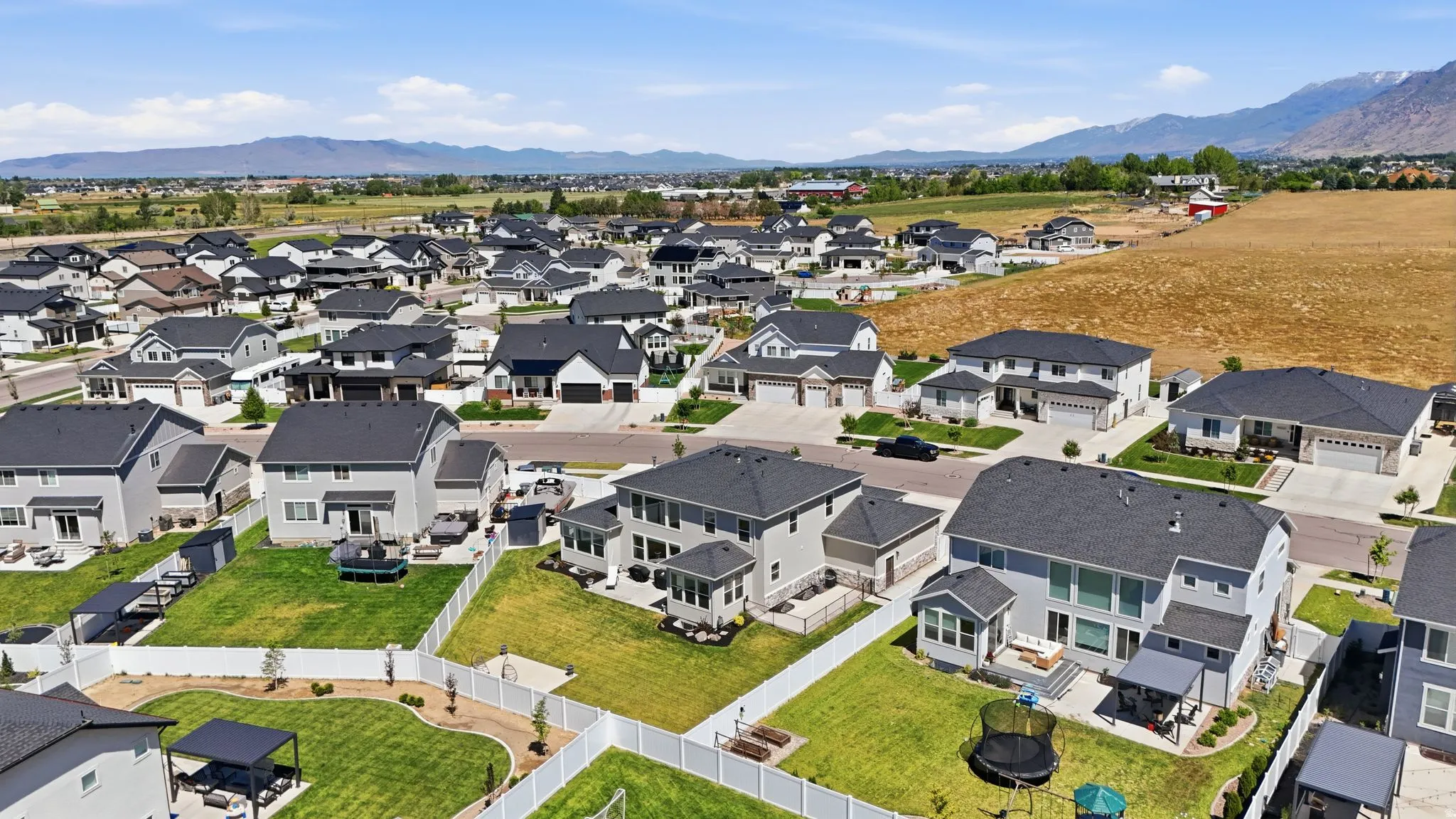 Expansive residential neighborhood featuring numerous contemporary homes with dark shingle roofs and light-toned siding