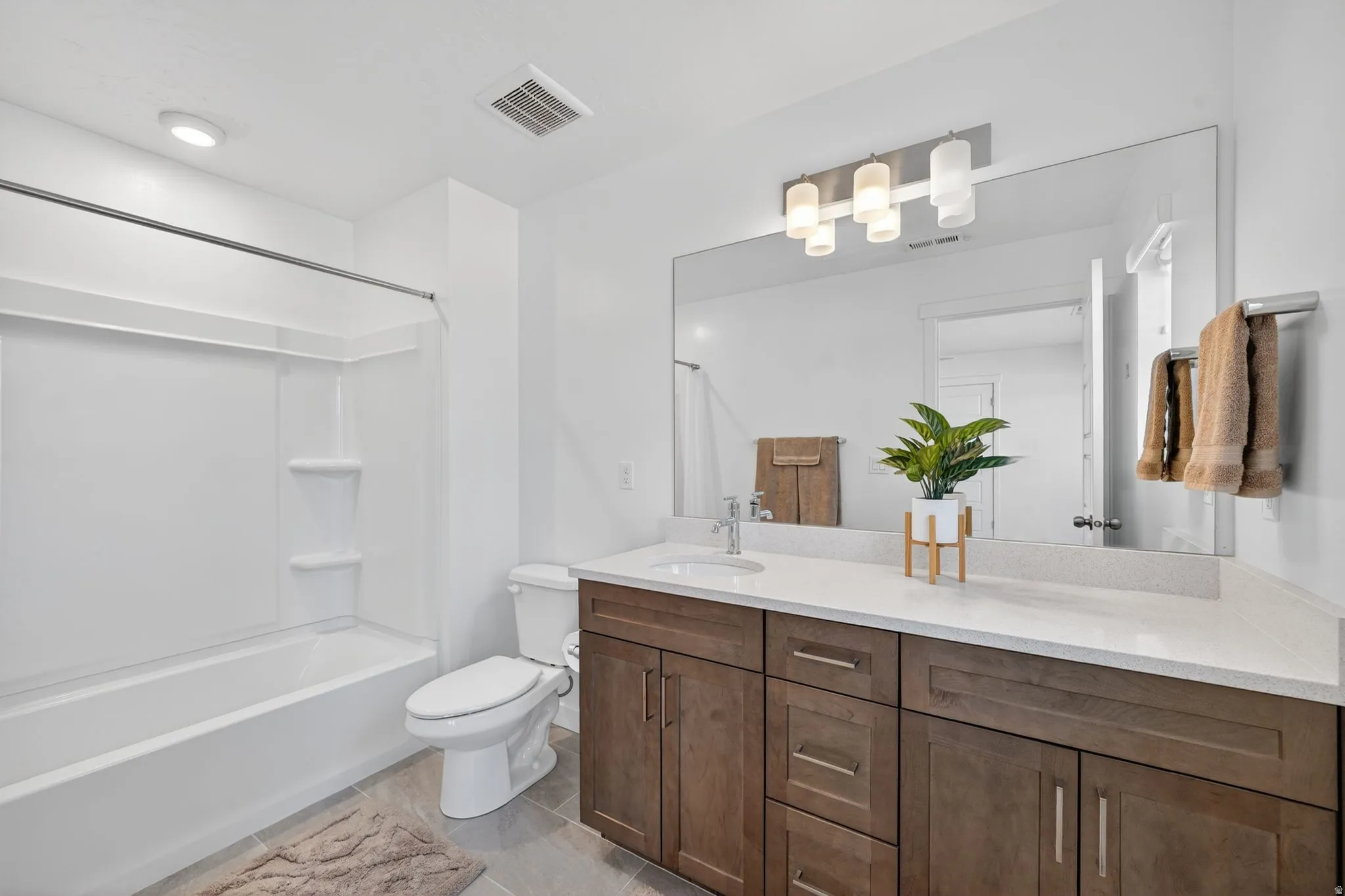 Spacious bathroom featuring a wood-finish double vanity, quartz countertop, and large mirror