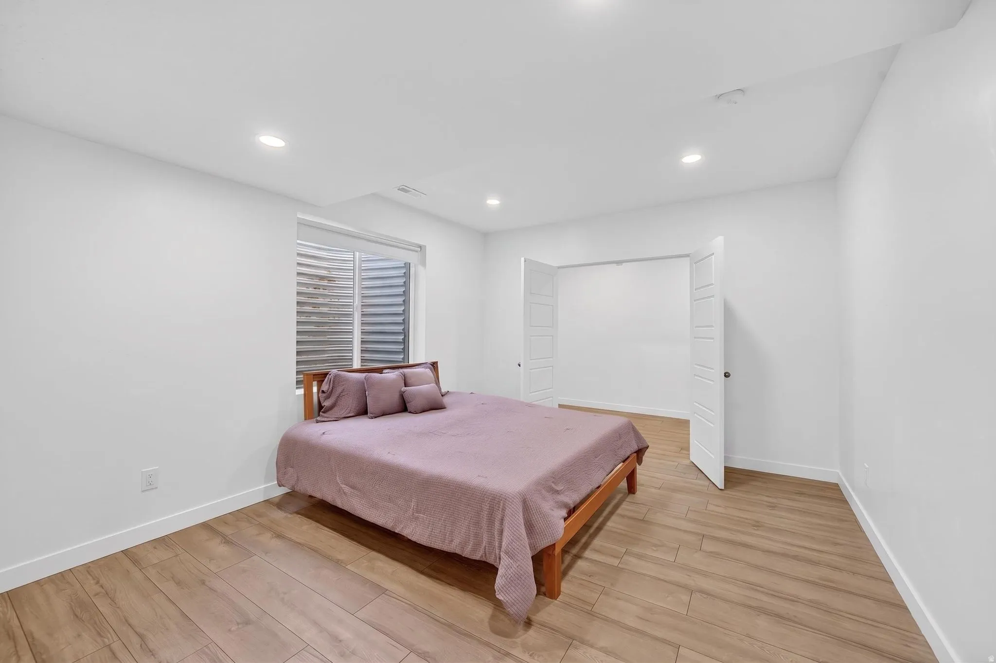 Room featuring wood-finish flooring, recessed lighting, and a window with horizontal blinds
